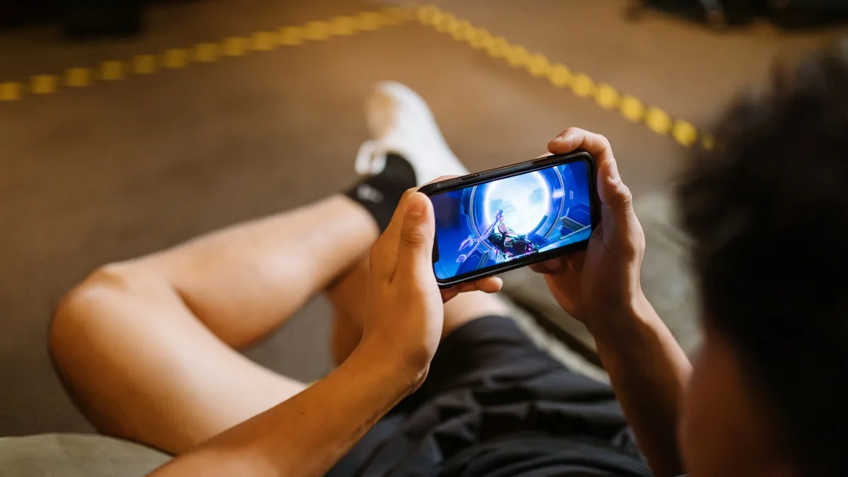 Bir akıllı telefon üzerinde oyun oynayan bir kişinin elleri