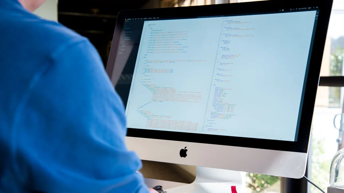 Ofis ortamında çalışan bir yazılımcının monitöründen kod akışını incelediği an.