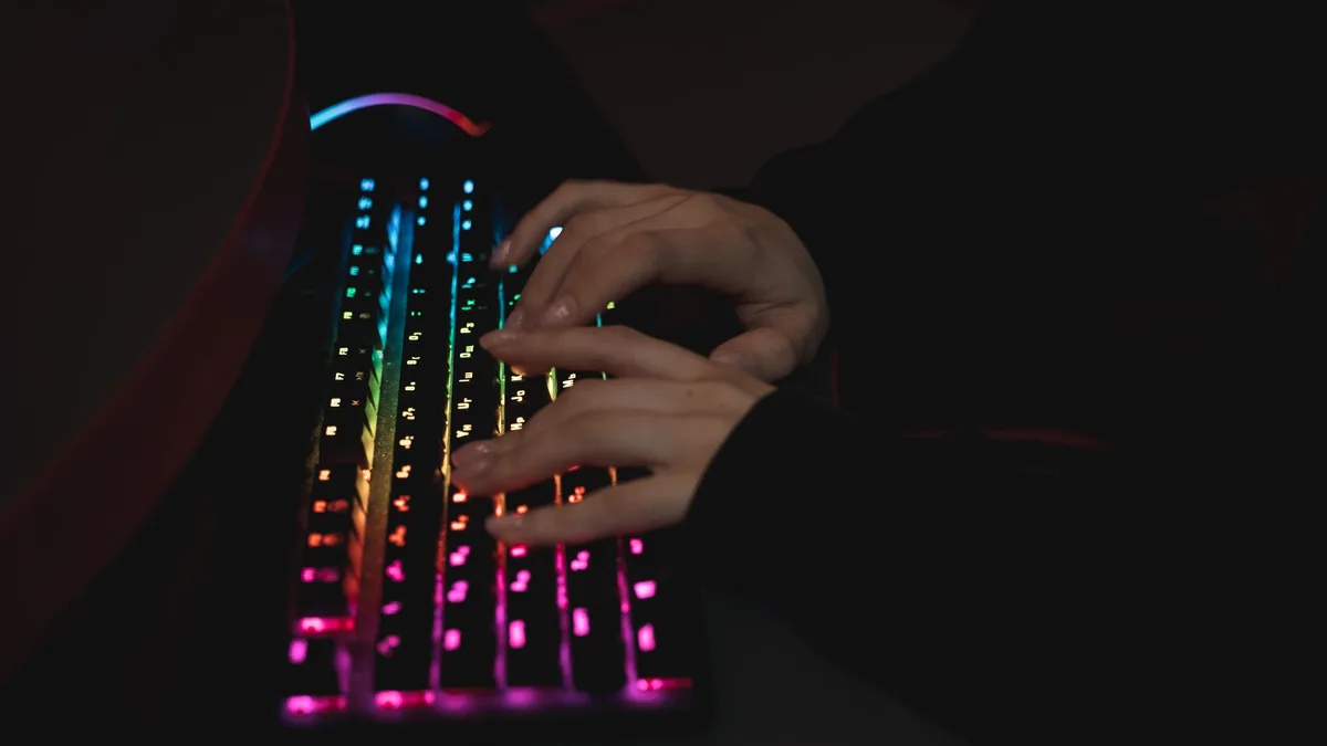 Çalışma masasında RGB aydınlatması açık şekilde konumlandırılmış kablolu oyuncu klavyesi