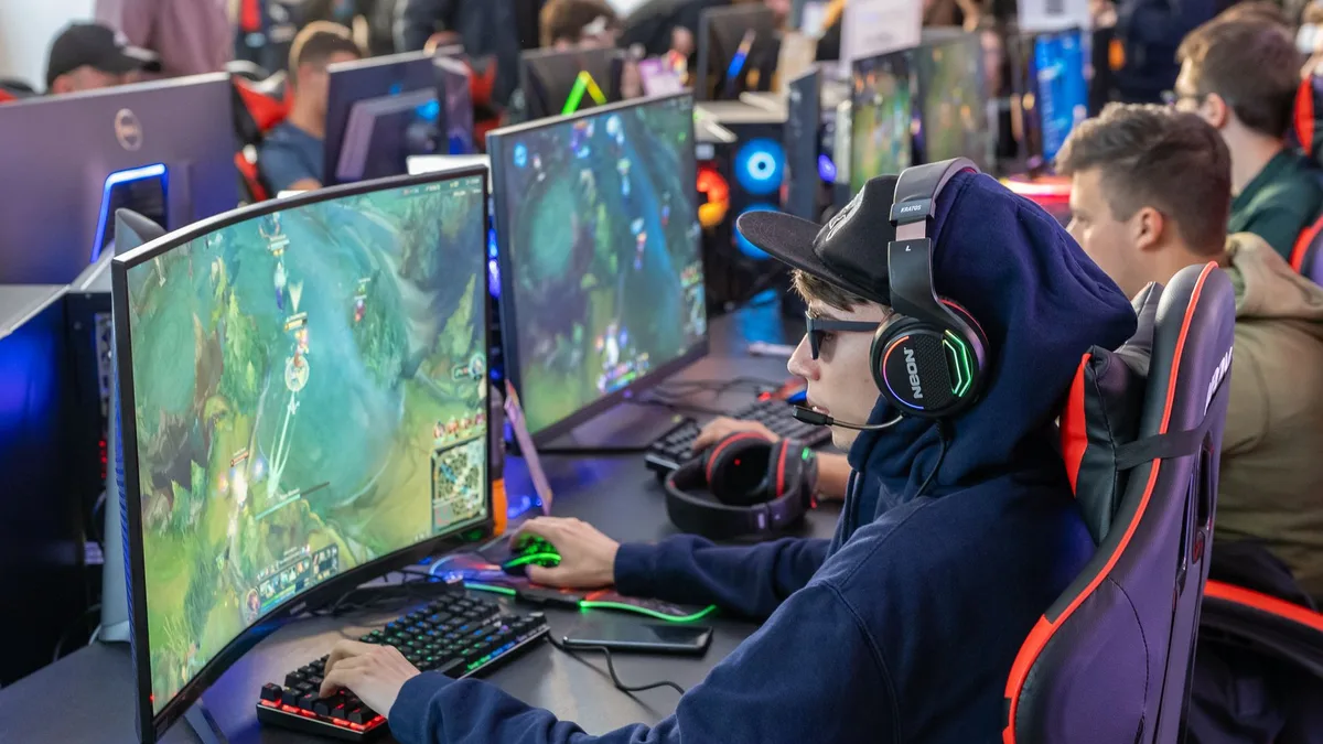Karanlık odada yüksek performanslı oyun monitörü kullanan bir oyuncu
