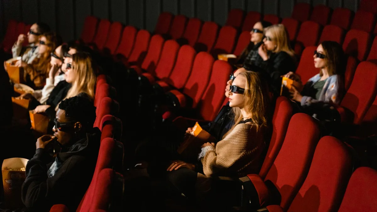 Karanlık bir sinema salonunda film izleyen seyirciler