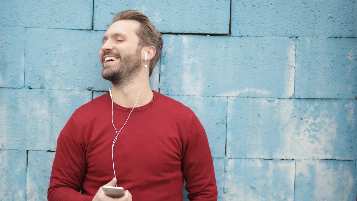 Akıllı telefonundan kulaklıkla müzik dinleyen bir kişi
