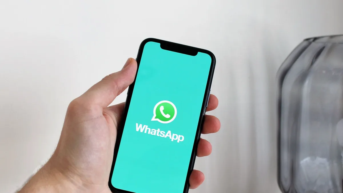 Telefonu elinde tutarak mesajlaşma uygulamasını inceleyen bir kişi.