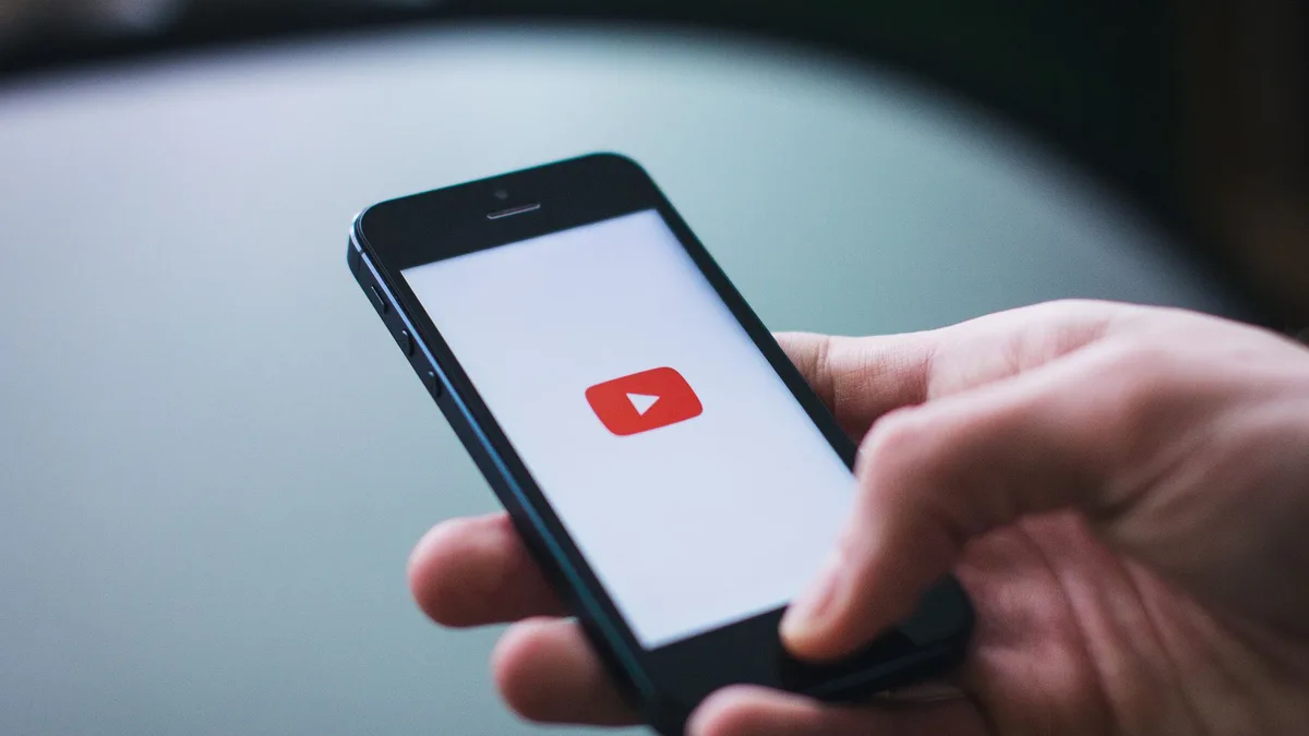 Karanlık ortamlarda akıllı telefon üzerinden YouTube akışında gezinen bir kişinin eli